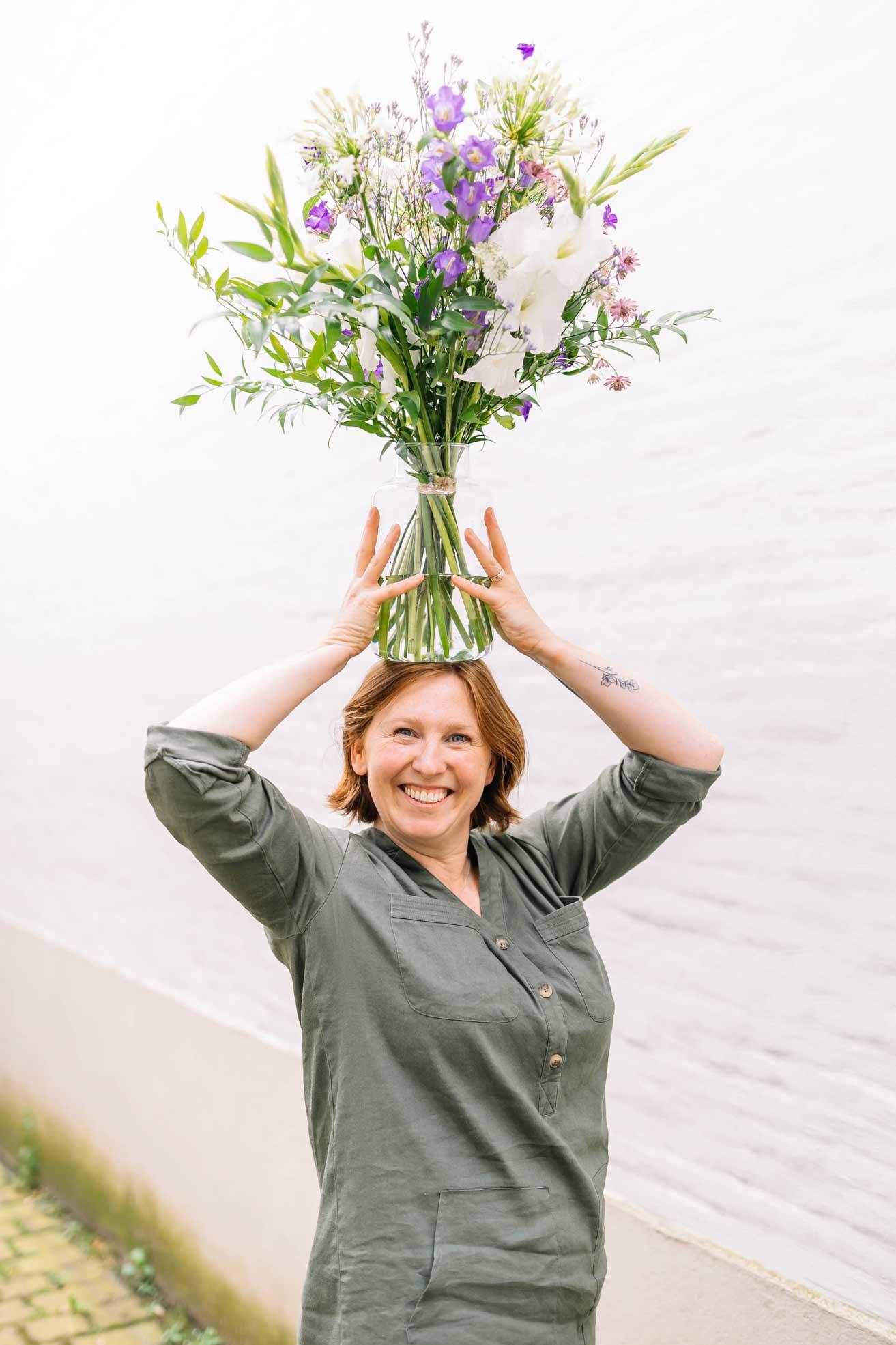 Kim met een vaas bloemen Kim houdt boven haar hoofd een vaas vast met een prachtig kleurrijk boeket verse snijbloemen